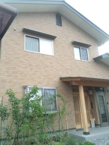 una casa de ladrillo marrón con tres ventanas. en 「けったもん」へようこそ！2階の1室でゆっくり休めます！ en Nagano