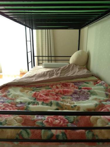 Una cama en un dormitorio con una manta de flores. en 「けったもん」へようこそ！2階の1室でゆっくり休めます！ en Nagano