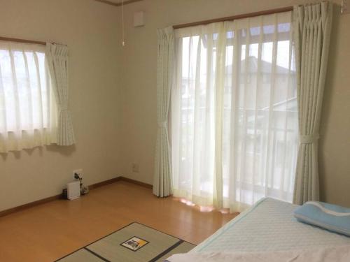 a bedroom with a bed and a large window at 「けったもん」へようこそ！2階の1室でゆっくり休めます！ in Nagano