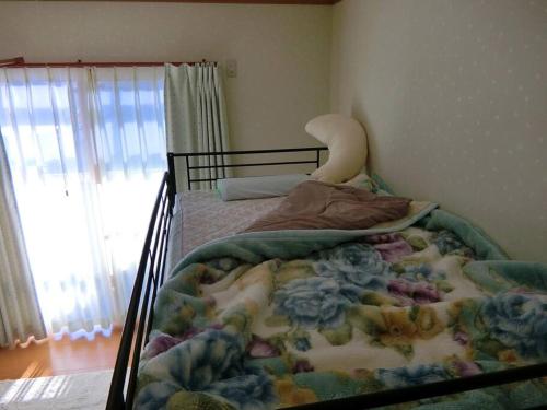 a bed with a blanket on it in a bedroom at 「けったもん」へようこそ！2階の1室でゆっくり休めます！ in Nagano