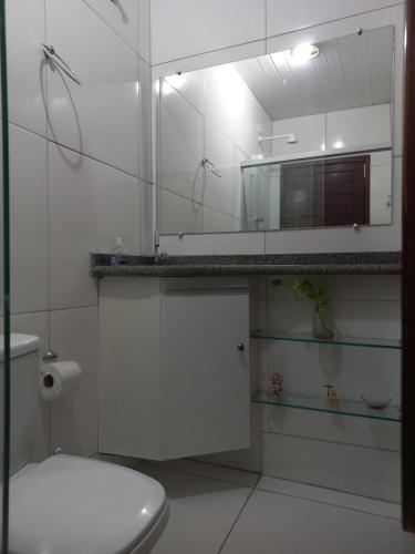 a white bathroom with a toilet and a mirror at Pousada Residencial acochego caririense in Juazeiro do Norte