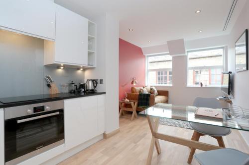 a kitchen and dining room with a glass table at Barbican Serviced Apartments in London