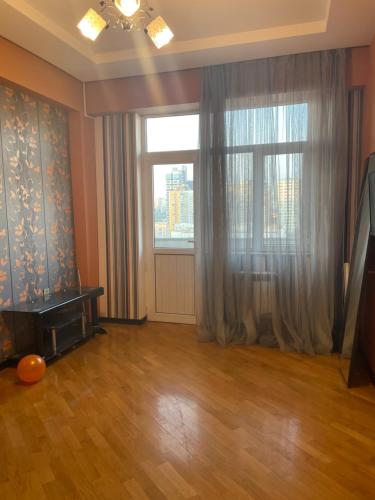 sala de estar vacía con ventana grande y suelo de madera en Khatai Apartment en Bakú