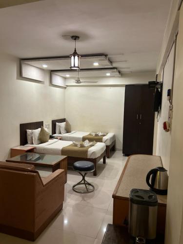 a living room with two beds and a table at Hotel The Excellency in Surat