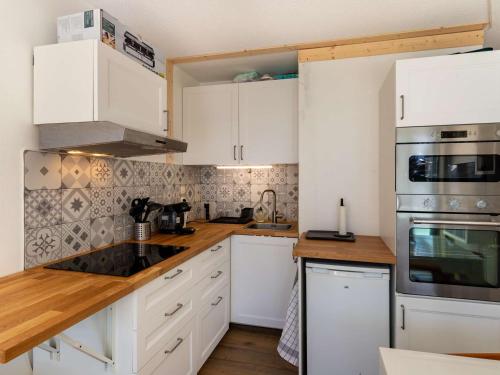 une cuisine avec des armoires blanches et des comptoirs en bois dans l'établissement Studio cabine 6 pers. proche pistes avec balcon et casier à ski - FR-1-400-124, à Eaux-Bonnes