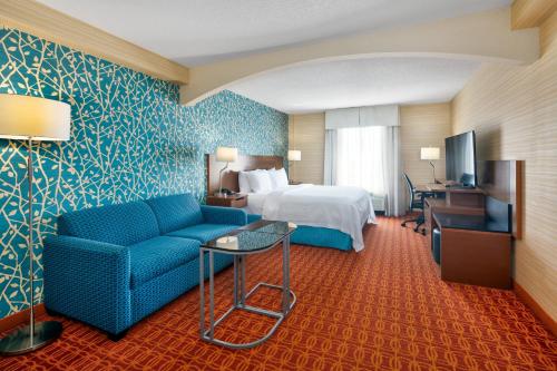 a hotel room with a bed and a blue couch at Fairfield Inn & Suites by Marriott Toronto Airport in Mississauga