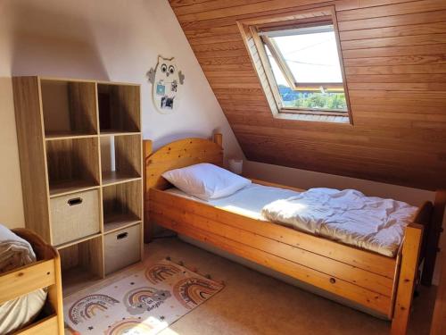 une chambre avec un lit en bois et une fenêtre dans l'établissement Chaleureux Penty, bord de mer, Pointe de Dinan, à Crozon