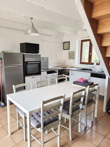 - une cuisine avec une table et des chaises blanches dans l'établissement Chaleureux Penty, bord de mer, Pointe de Dinan, à Crozon