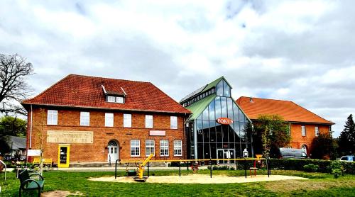 un gran edificio de ladrillo con un parque infantil delante de él en Hotel Fokus en Emsbüren