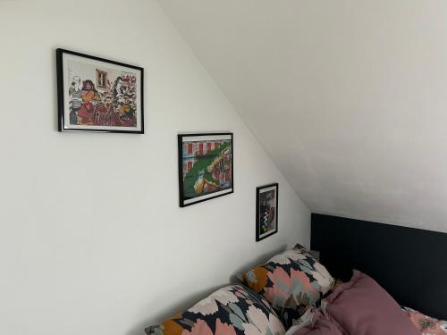 ein Wohnzimmer mit Sofa und Bildern an der Wand in der Unterkunft CHAMBRE PRIVÉE dans une maison in Argenteuil