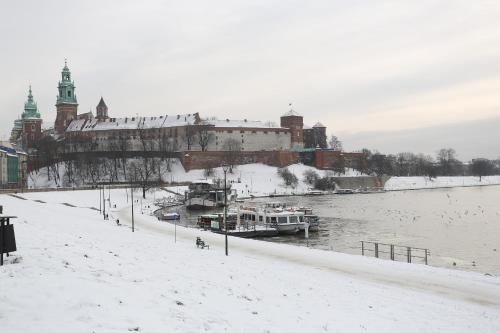 a snowy city with boats docked on a river at Cozy Studio perfect for couples, Cracow Old Town in Krakow