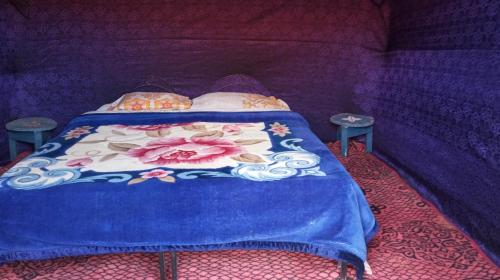 un letto con piumone blu e due tavoli di Gambe Camp ad Adrouine