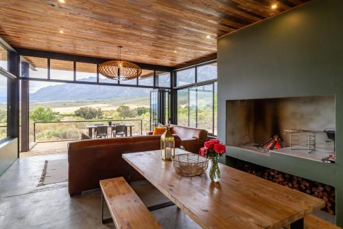 ein Wohnzimmer mit einem Tisch und einem Kamin in der Unterkunft Steenbok farm cottages Kingfisher Cottage in Wolseley