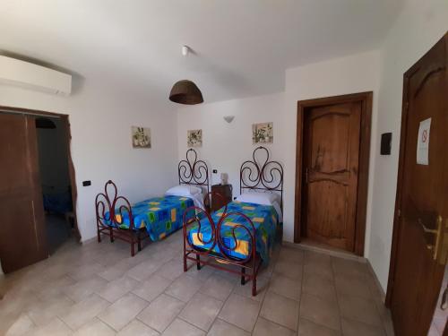 a room with two beds and two chairs and a door at Casale del Gufo in Chiaravalle