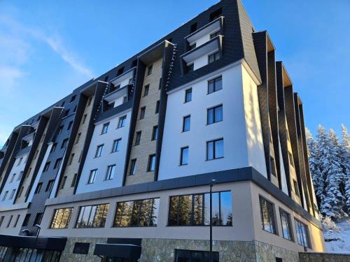 un edificio blanco con techo negro en Apartmani Zlatni Javor 504 & 514, en Jahorina