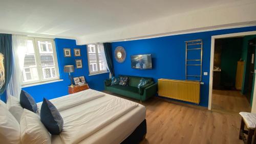 a bedroom with blue walls and a bed and a couch at Boutique Hotel & Bio Wirtshaus Schwarzer Bock in Ansbach