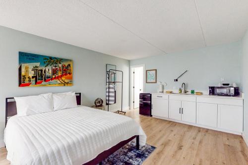 a bedroom with a white bed and a kitchen at Capri 108 in Marco Island