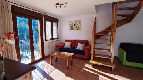 ein Wohnzimmer mit einem roten Sofa und einer Treppe in der Unterkunft Apartamentos Mobison in Salinas de Bielsa
