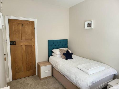 a small bedroom with a bed and a wooden door at Sunbeams and ice creams in Scarborough