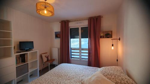 a bedroom with a bed and a television and a window at T3 STANDING CENTRE STATION VALBERG in Valberg