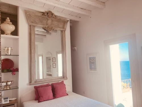 a white room with a mirror and red pillows at B&b Casa Maredentro in Monopoli