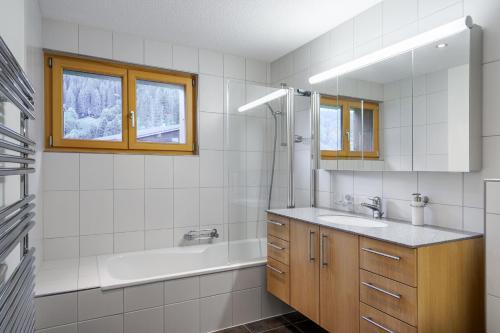 a bathroom with a tub and a sink and a tub and a mirror at Chalet Aquila 5 in Wengen