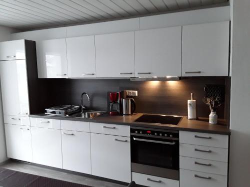 a kitchen with white cabinets and a stove top oven at Bobis Ferienwohnung in Wildpoldsried