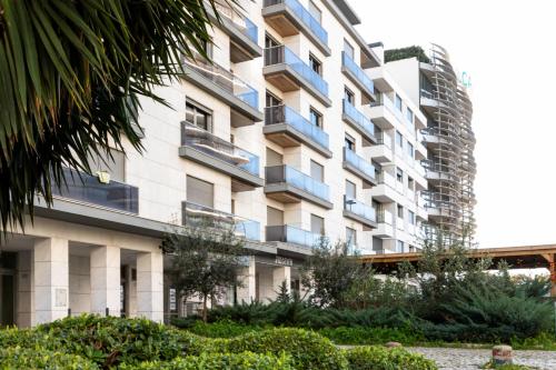 an apartment building with blue balconies and bushes at Apartamento Lisboa Sete Rios in Lisbon