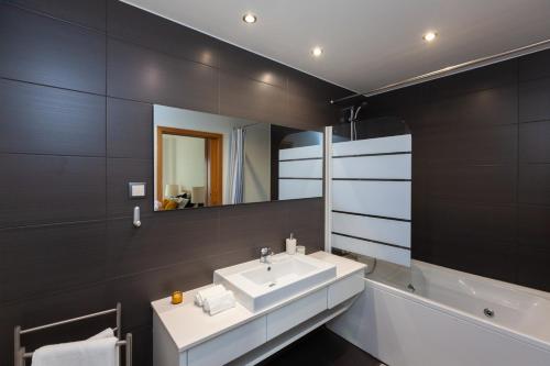 a bathroom with a sink and a mirror and a tub at Apartamento Lisboa Sete Rios in Lisbon