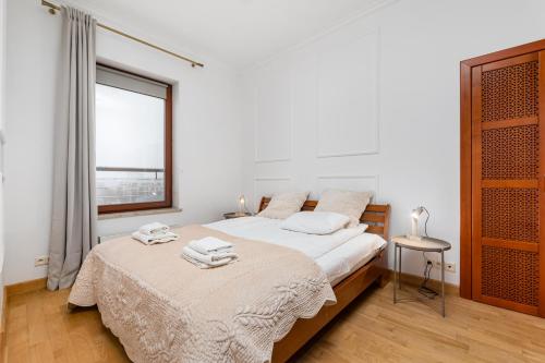 ein weißes Schlafzimmer mit einem Bett mit Handtüchern darauf in der Unterkunft Tagore 3 by Homeprime in Warschau