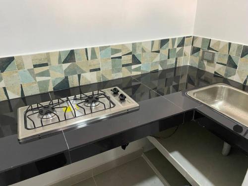 a kitchen counter with a stove and a sink at Comfortable apartment very close to the airport in Cúcuta