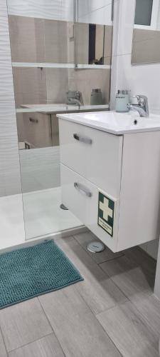 a white bathroom with a sink and a mirror at Chinde Guesthouse in Lisbon