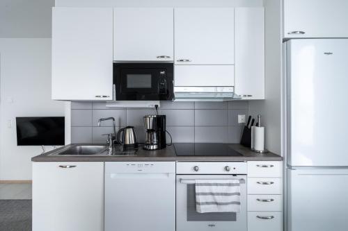 a white kitchen with a sink and a microwave at Lumiapartment1 in Rovaniemi