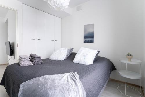 een slaapkamer met een groot bed met witte muren bij Lumiapartment1 in Rovaniemi