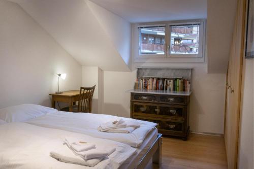um quarto com uma cama, uma janela e uma secretária em Chalet Tilia Penthouse em Wengen