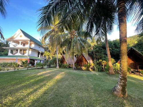 a large house with palm trees in front of it at Binucot Lodge in Romblon