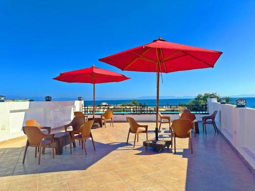 a patio with tables and chairs and red umbrellas at King House in Sharm El Sheikh