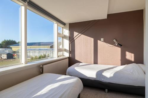 twee bedden in een kamer met een groot raam bij Vakantiehuis Rust in de onruste in Kamperland