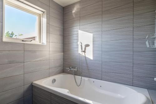 een badkamer met een wit bad en een raam bij Vakantiehuis Rust in de onruste in Kamperland