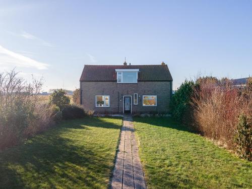 a house on a grassy field with a path leading to it at Vakantiehuis Rust in de onruste in Kamperland