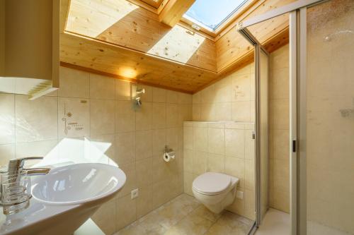 ein Badezimmer mit einem Waschbecken, einem WC und einem Dachfenster in der Unterkunft Kinohaus 7 in Wengen