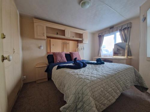 a bedroom with a large bed with blue towels on it at Caravan F7 Aberystwyth holiday village in Aberystwyth
