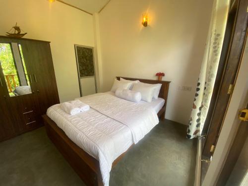 um quarto com uma cama grande e lençóis brancos em Jungle Beach Inn em Unawatuna