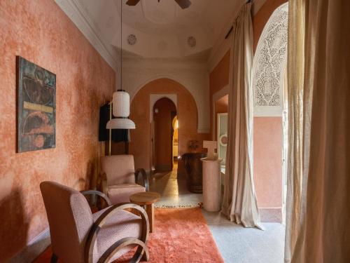 a living room with orange walls and a table and chairs at Riad Brummell Medina in Marrakesh
