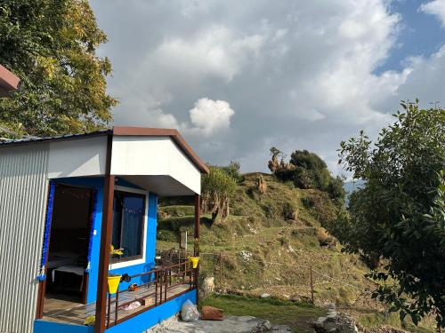 a blue and white house with a hill in the background at Lake Haven Resort, Sari, Chopta in Sari