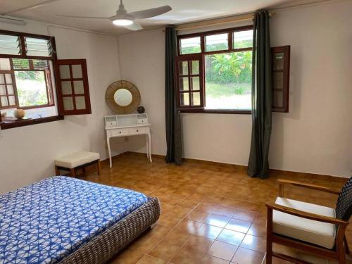 a bedroom with a bed and a table and windows at Zayann Zen in Gourbeyre