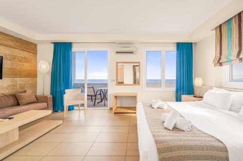 um quarto de hotel com uma cama grande e um sofá em Glaros Beach Hotel em Hersonissos