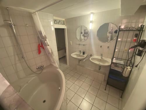 a bathroom with two sinks and a tub and two mirrors at 3x Ferienwohnung I Apartment I Free Parking I WiFi I ruhige Lage in Anröchte