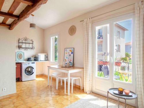 a living room with a table and a kitchen with a window at Appartement climatisé en plein centre avec balcon in Saint-Jean-Cap-Ferrat