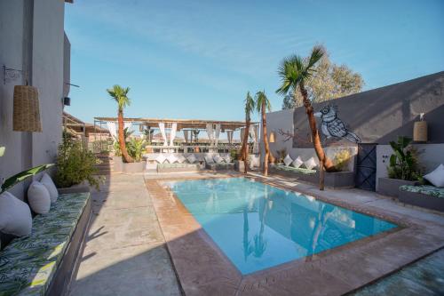 a swimming pool with palm trees and a building at Piccolo Bike Hotel in Lalla Takerkoust